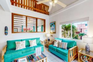 a living room with green couches and windows at Palm @ Caribe Island in San Pedro