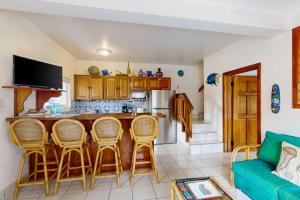 a kitchen with a bar with chairs and a couch at Palm @ Caribe Island in San Pedro