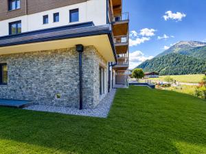 a house with a green lawn next to a building at BASE Achensee - Opening August 2026 in Achenkirch