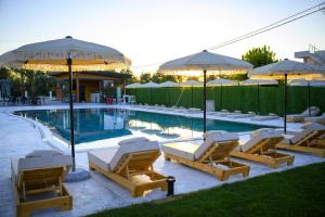 a swimming pool with lounge chairs and umbrellas at Kompleksi Turistik ARMANDO in Tale