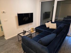 a living room with a blue couch and a tv at Apartman Rena in Ivanec