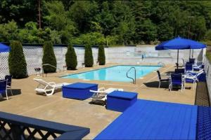 a swimming pool with blue chairs and umbrellas at Gilford Beachfront Stay, Pool, WiFi & Parking Incl in Laconia