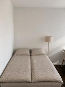 a bed in a white room with a lamp at NØ -Central Apartment Odense C in Odense
