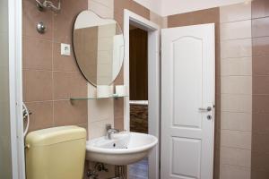 ein Badezimmer mit Waschbecken, Toilette und Spiegel in der Unterkunft Hostel Centuria in Pula