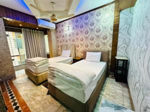 two twin beds in a room with a wall at Sea Shell Service Apartment in Bāiljuri