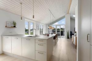 a kitchen with white cabinets and a table with chairs at TV1737-Bindslev-Mellemklitvej-23 in Tversted