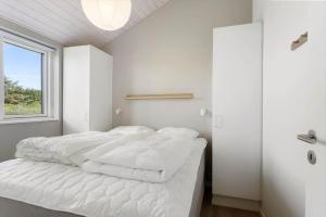 a bedroom with a bed with white sheets and a window at TV1737-Bindslev-Mellemklitvej-23 in Tversted