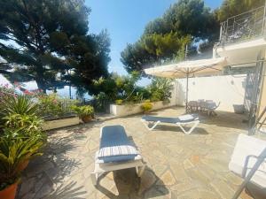 a patio with two lounge chairs and an umbrella at Villa Fronte Mare Con Terrazza in Marina di Andora