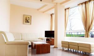 a living room with white furniture and a large window at Hotel Copernicus in Lubawa