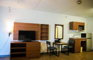 a room with a desk with a tv and a table with chairs at MainStay Suites Chicago Hillside in Hillside