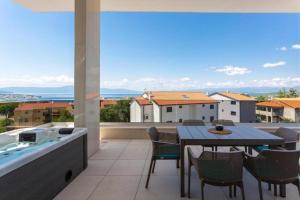 a balcony with a table and chairs and a bath tub at Penthouse Apartment Maya with Pool and Jacuzzi in Sveti Anton