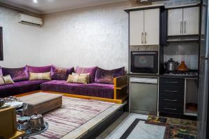 a living room with a purple couch and a kitchen at dakhla home in Aït Krad