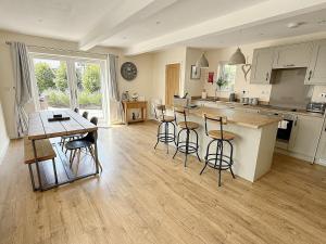 a kitchen with a table and bar stools in it at Barn Cottage in Minehead +15 photos