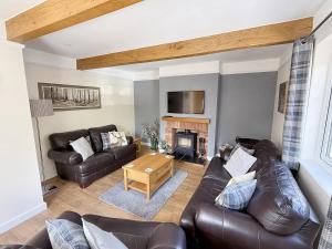a living room with leather furniture and a fireplace at Barn Cottage in Minehead