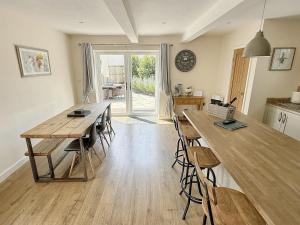 a kitchen with a wooden table and bar stools at Barn Cottage in Minehead