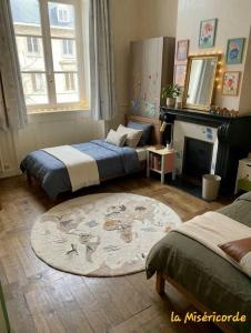 a bedroom with two beds and a fireplace and a rug at La Miséricorde-Deluxe room with kids room in Coutances
