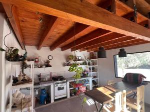 Eine Küche mit Holzdecke, einem Tisch und einem Herd in der Unterkunft Maima in Maimará