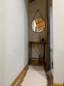 a hallway with a mirror and a table with a rug at Espaço Luna in Gramado