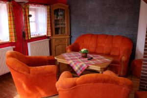 a living room with two orange chairs and a table at Farma Wenet in Broumov