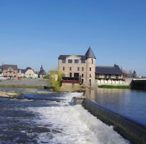 a building on the side of a river with water at Ma maison du port in Guipry-Messac