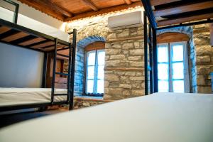 a bedroom with two bunk beds and two windows at Beds Hostel in Gjirokastër