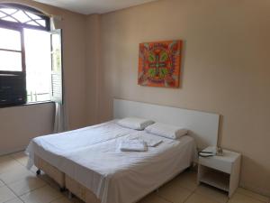 Un dormitorio con una cama blanca con una foto en la pared en Cachoeira Apart Hotel, en Cachoeira