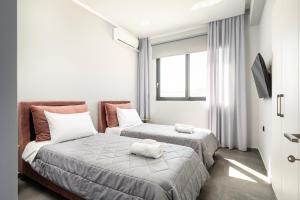 two beds in a room with white walls and windows at Thalori villa 2 in Psalidi +33 photos