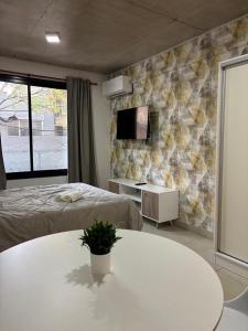 a room with two beds and a table and a tv at Bnb loft XlV - Pasos Bv oroño y Av pellegrini in Rosario