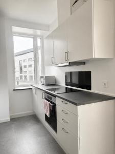 a kitchen with white cabinets and a black counter top at NØ -Central Apartment Odense C in Odense