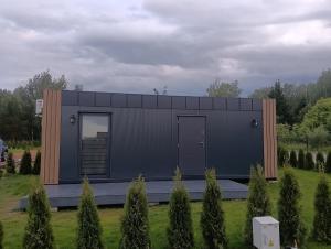 a small black building with a door in a field at Domki u Krukow in Łuka +1 photo