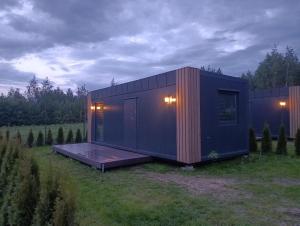 a black tiny house sitting on top of a field at Domki u Krukow in Łuka