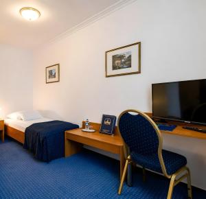 a hotel room with a bed and a desk with a television at HOTEL ATLANTA Darmstadt SUPERIOR in Darmstadt