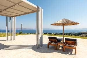 two chairs and an umbrella on a patio at Thalori villa 2 in Psalidi