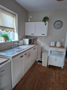 a kitchen with white cabinets and a sink at Judys View in Cashel