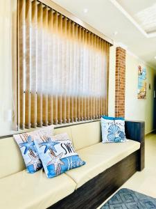 a couch with pillows on it in front of a window at Recanto Céu & Mar Casa de Praia em Manguinhos São Francisco de Itabapoana in São Francisco de Itabapoana