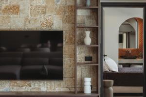 a living room with a television on a brick wall at Serenita luxury villa in Zakynthos +10 photos
