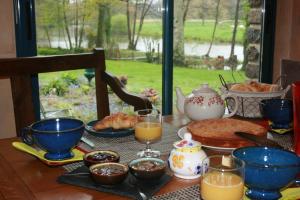 een tafel met een ontbijt van eten en sinaasappelsap bij Au Pont Ricoul in Saint-Pierre-de-Plesguen