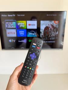a person holding a remote control in front of a tv at Pousada da Mariinha in São Lourenço +58 photos