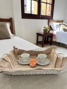a tray with two cups and plates on a bed at Pousada da Mariinha in São Lourenço