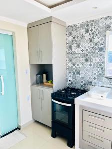 a kitchen with a black stove and a sink at Recanto Céu & Mar Casa de Praia em Manguinhos São Francisco de Itabapoana in São Francisco de Itabapoana