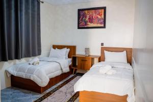 a bedroom with two beds and a table and a window at oasis house in Takchrirt