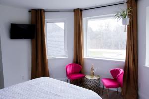 a bedroom with pink chairs and a bed and a window at 4 Guest Suite with Waterfront Views at Fancie's PEC - Suite 2 in Belleville
