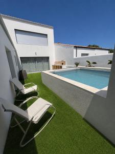 a pair of chairs sitting on a lawn next to a swimming pool at Maison des Oliviers in Puilboreau