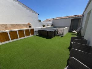 a patio with green grass and a table and chairs at Maison des Oliviers in Puilboreau