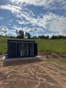 a black building on a dirt road in a field at Dolina snów in Kruklanki +1 photo