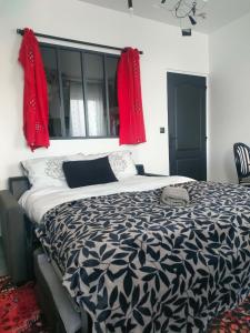 a bedroom with a black and white bed with red curtains at Maison La Suite 27 in Guingamp