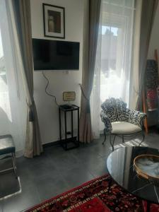 a living room with a tv and a chair and a table at Maison La Suite 27 in Guingamp