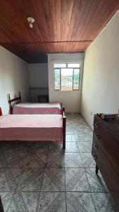 a bedroom with two beds and a dresser and a window at downtown Teófilo Otoni in Teófilo Otoni