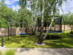 a swing set around a tree in a yard at Domy Kopułowe 5th Wymiar in Skrybicze