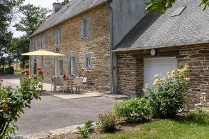a brick house with a table and an umbrella at Ti Coet Salio - Nature & calme près de Guerlédan in Guerlédan